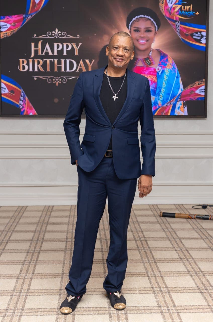 Dr. Keith Clint Harrington posing in front of the Principal Princess's birthday backdrop